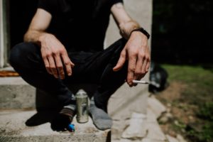 kucający człowiek z papierosem w ręku i alkoholem